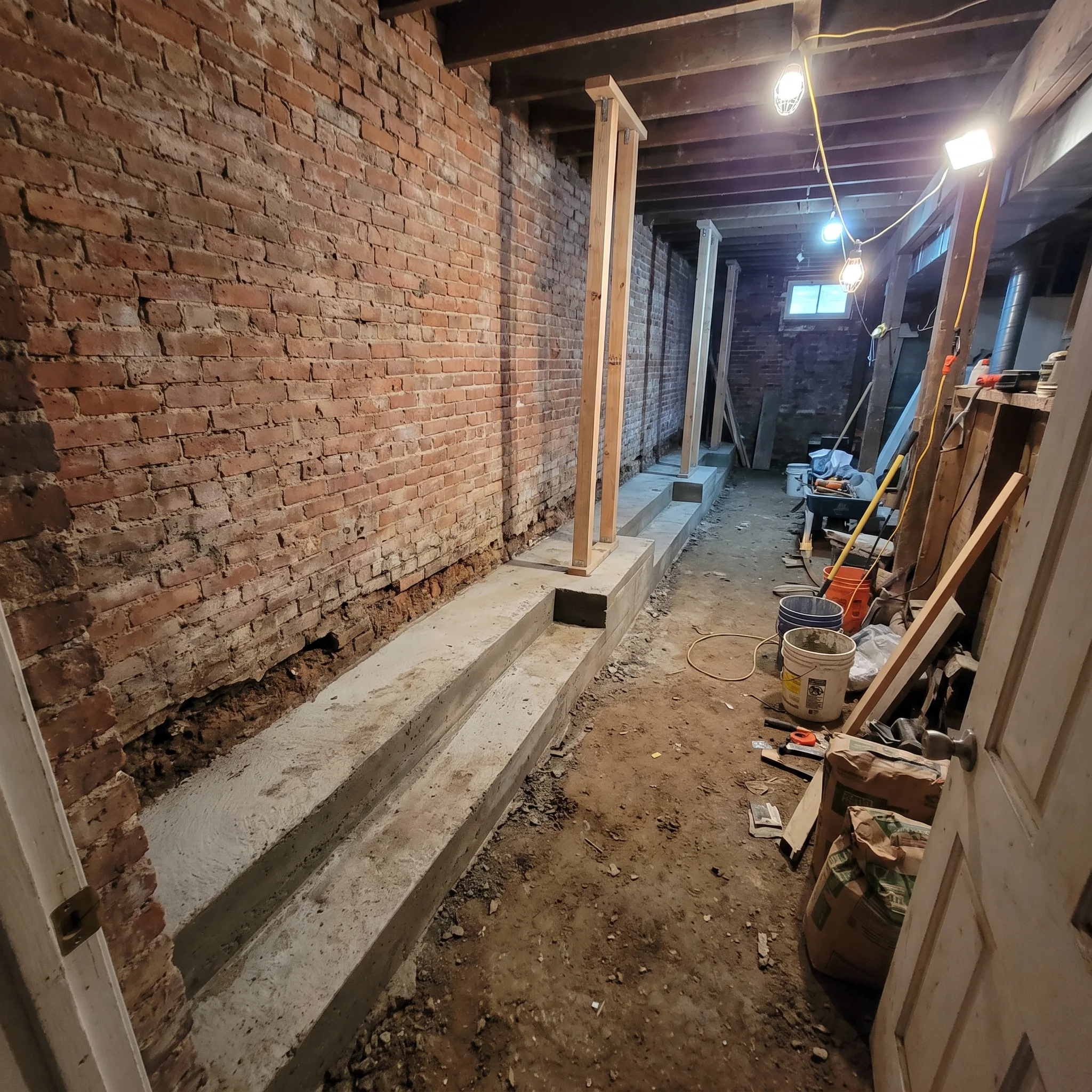 Bench footing basement lowering construction beneath a row house foundation in Beasley, Hamilton